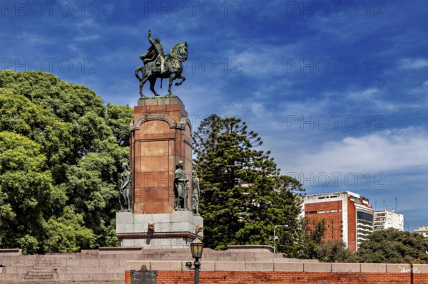 An equestrian monument on a pedestal surrounded by trees and buildings under a blue sky, The city of Buenos Aires in Argentina