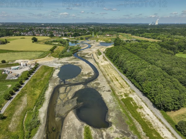 Dortmund, Castrop-Rauxel, North Rhine-Westphalia, Germany - River renaturalisation, renaturation of the Emscher, flood retention basin HRB Mengede. A new floodplain landscape is being created at the Emscher-Auen farm, expanding the area for flood protection during heavy rainfall and for biodiversity. The previously straightened Emscher is being given curves again and can meander through its new floodplain. Following the construction of a parallel sewer, the Emscher has been completely free of sewage since 2022. The river was previously an open, above-ground mixed water channel with rainwater and wastewater. At the back right, the Uniper coal-fired power plant Datteln 4 power station