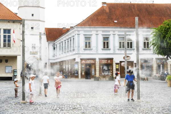 Water mist system in the city centre of Trencin, children use the refreshment in the summer heat, Trencín, Slovakia