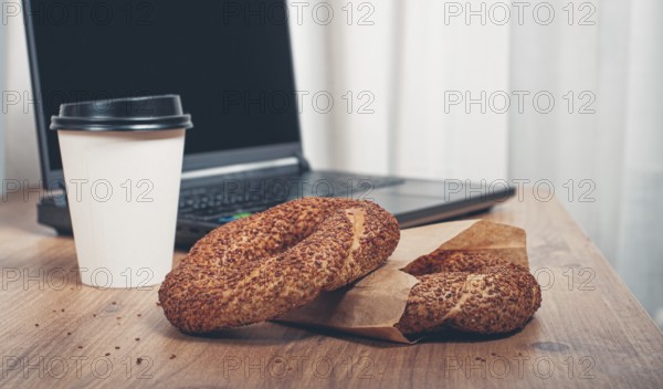Simits with coffee on a wooden table, with a laptop, in a cozy working environment, snack, breakfast, no people