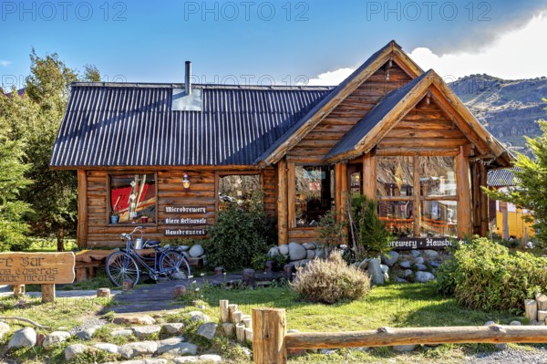 Cosy wooden house with a small garden, mountains behind it in the sunny daylight, the village of El Chalten in Patagonia, Argentina