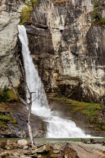 A waterfall cascades over rocky cliffs into a forest, surrounded by rocks and vegetation, waterfall in Patagonia Argentina
