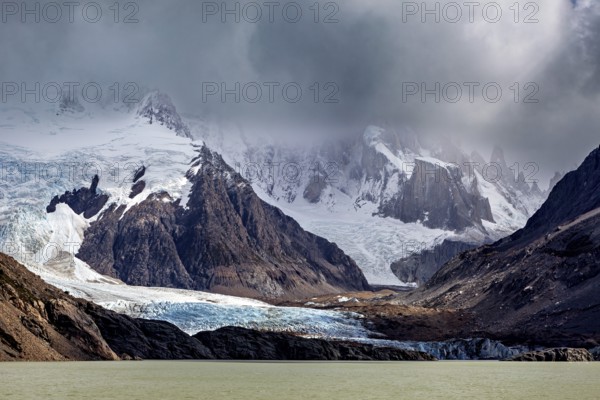 Dramatic glacier with rocks and threatening clouds form an impressive backdrop, The Perito Moreno glacier in Argentina