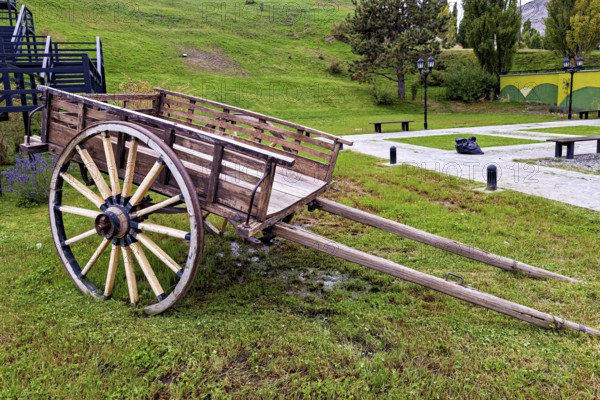Weathered carriage on a green surface surrounded by hills and trees, Historical horse-drawn carriage or coach with wagon wheels in Patagonia