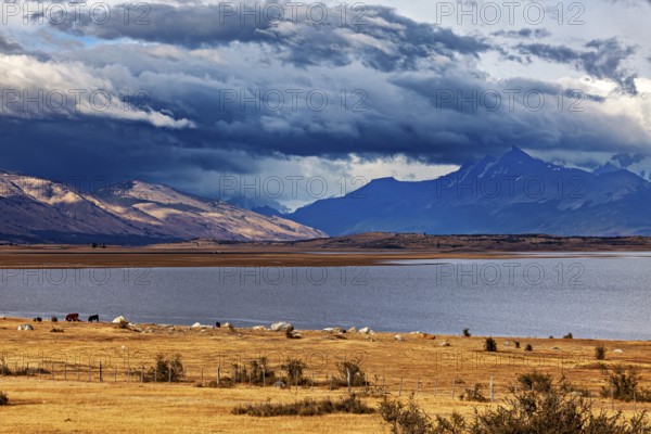 A wide lake under dramatically threatening clouds, surrounded by majestic mountains: the Patagonian landscape near El Chalten in Argentina