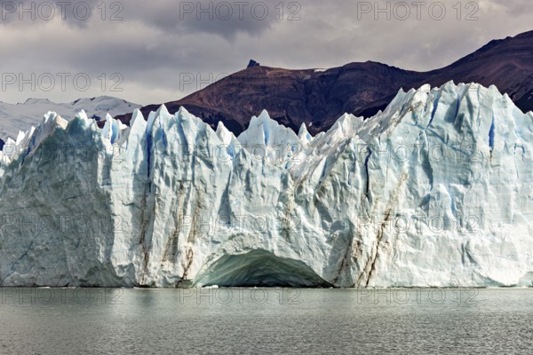 Impressive ice wall of a glacier under a cloudy sky near a mountain, The glacier of Perito Moreno in Argentina