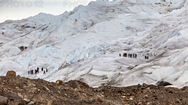 Hiking group on a glacier expedition over icy surfaces and boulders, The Perito Moreno glacier in Argentina