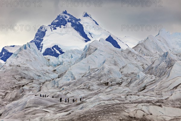 Adventurous climbers on a glacier with looming mountains and clouds, The Perito Moreno glacier in Argentina