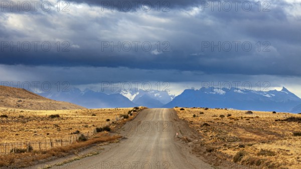 A long gravel road leads to a distant mountain range under a cloudy sky, The Patagonian landscape near El Chalten in Argentina