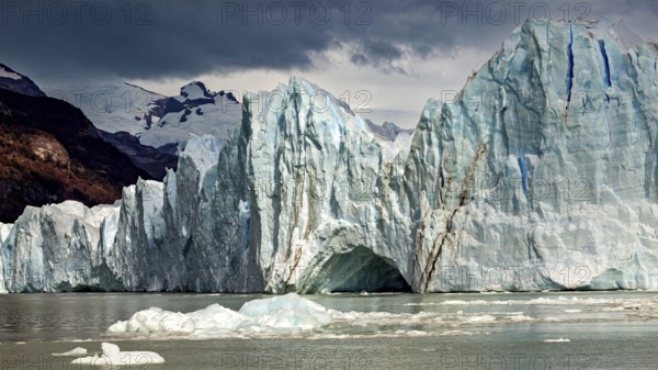 Majestic glacier in the water with dramatic clouds and mountains in the background, The Perito Moreno glacier in Argentina