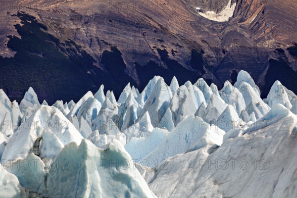 Pointed ice formations in front of a dark mountain landscape with an impressive natural backdrop, the blue ice of the Perito Moreno Glacier in Patagonia, Argentina