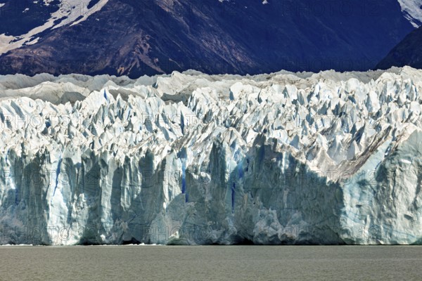 Detailed view of a massive blue glacier against a mountain backdrop, The Perito Moreno glacier in Argentina