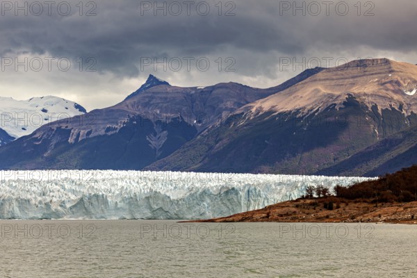 Impressive glacier front with dramatic sky and mountainous backdrop, The Perito Moreno glacier in Argentina