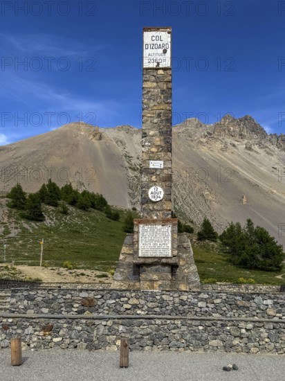 At Alpine pass Col de l'Izoard d'Izoard 2360 metres high road pass at pass summit of mountain road pass road 1934 erected altitude marker monument stele memorial column made of natural stone in memory of dedicated to General Baron Berge and workers of road construction, Cervières, Department Hautes-Alpes, Provence-Alpes-Cote d'Azur, France