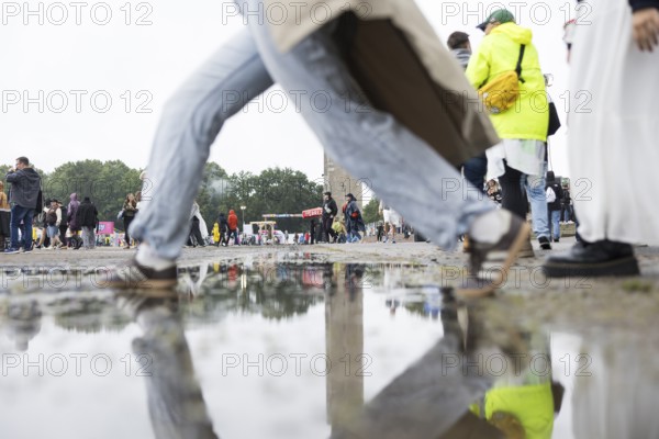 Festival-goers jump over a puddle of rain at the Lollapalooza Festival in the Olympic Stadium and on the Maifeld, Berlin, 12 July 2025