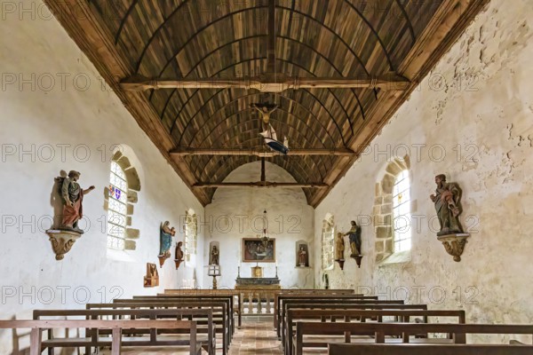 Interior view of a chapel with wooden ceiling, benches and statues on the walls, Pirou Castle in Normandy, France