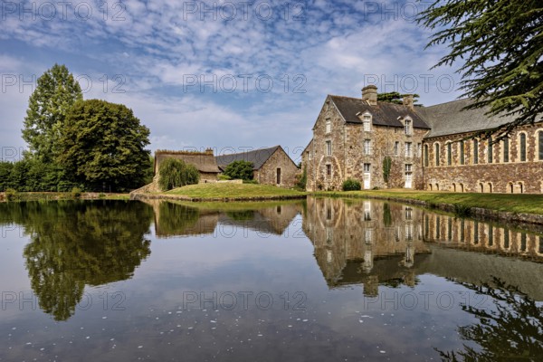 Historic castle on the shore of a lake with a clear reflection and surrounded by trees, The Abbey de La Lucerne in Normandy, France