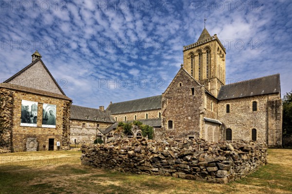 A church with adjoining ruins and stone walls under a blue sky, The Abbey de La Lucerne in Normandy, France