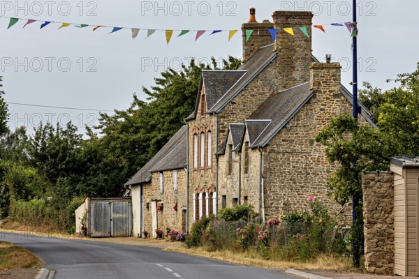 A traditional stone house on a rural road with festive garlands, Historic houses in Normandy, France