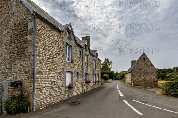 Traditional stone house on a quiet village street under a cloudy sky, Historic houses in Normandy, France