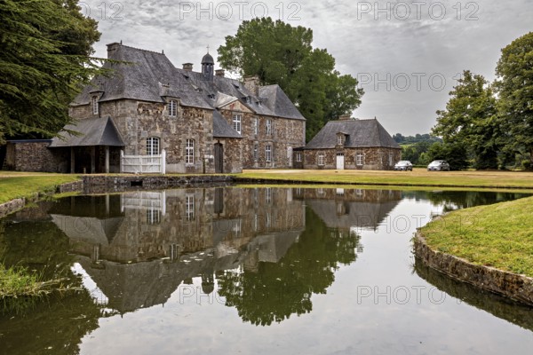 A castle with a pond in front of it, in which the building and the surrounding trees are reflected, The Abbey de La Lucerne in Normandy, France