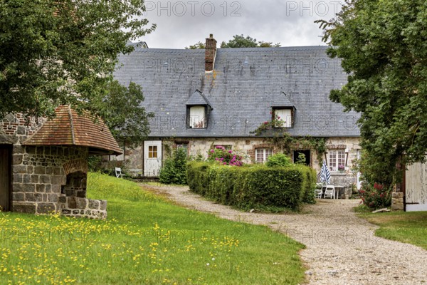 Idyllic farmhouse with garden and gravel path surrounded by green meadows, the historic mill village of Veules Les Roses in Normandy, France