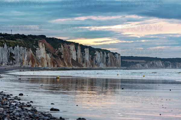 Rocky cliffs by the sea at sunset with a calm atmosphere and a cloudy sky, The cliffs near Dieppe in Normandy, France