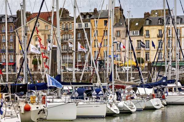 Sailing boats at a lively town harbour with colourful buildings and flags, The harbour of Dieppe in Normandy, France