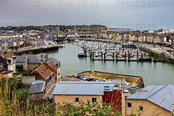 View of a busy harbour town with many boats and city buildings under a cloudy sky, The harbour of Dieppe in Normandy, France