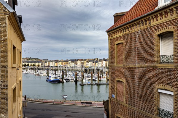 View of a harbour with boats through two brick buildings in the foreground, The harbour of Dieppe in Normandy, France