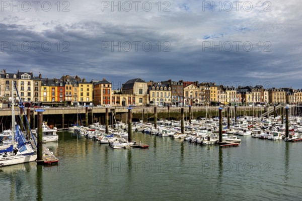 Historic buildings line a harbour full of boats under a cloudy sky, The harbour of Dieppe in Normandy, France