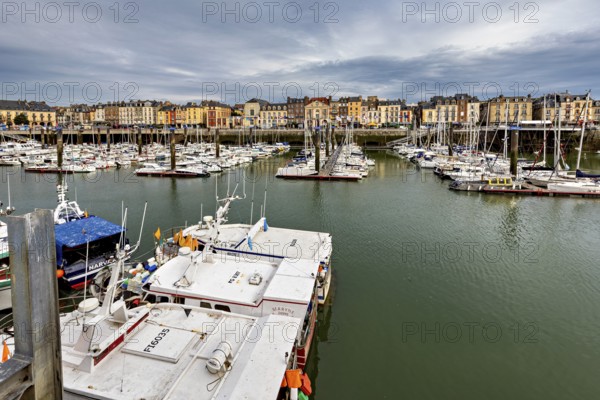 Boats moored in the quiet harbour, surrounded by historic buildings under a cloudy sky, The harbour of Dieppe in Normandy, France