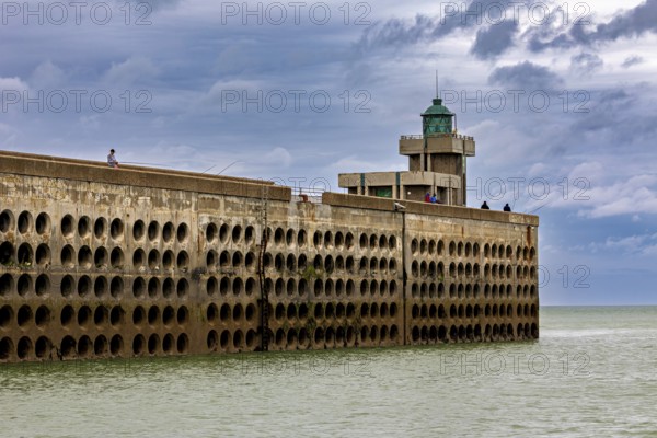 Long harbour wall with lighthouse, surrounded by the sea, under a sky with clouds, The harbour pier of Dieppe in Normandy, France