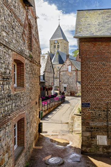 Idyllic village alley with pictures of the church and old brick houses in the sunshine, The historic mill village of Veules Les Roses in Normandy in France