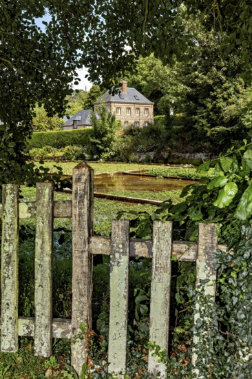 A cosy house behind an old, overgrown garden fence in a rural setting, the historic mill village of Veules Les Roses in Normandy, France