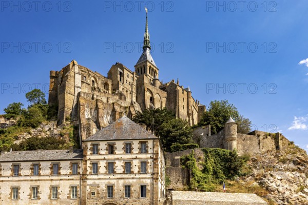 Imposing castle and fortress rising against a blue sky, with massive stone walls and towers, Mont Saint Michel in Normandy, France