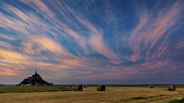 Mont Saint-Michel at sunset with dramatic sky and straw bales, Mont Saint Michel in Normandy, France