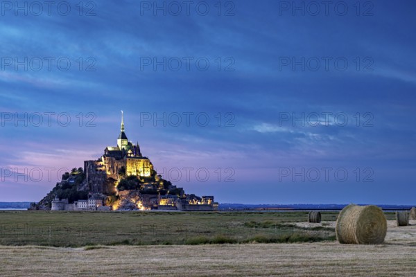 Mont Saint-Michel at dusk, illuminated with straw bales in the foreground, Mont Saint Michel in Normandy, France