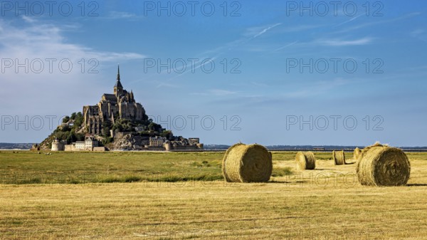 View of Mont Saint-Michel with bales of straw in a field under a clear sky, Mont Saint Michel in Normandy, France