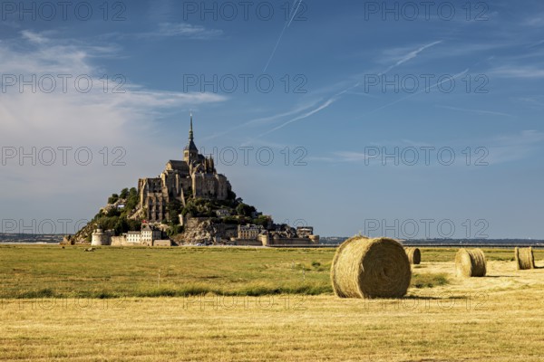 Landscape with Mont Saint-Michel and straw bales under a bright blue sky, Mont Saint Michel in Normandy, France