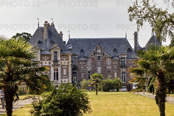 A historic castle with towers, surrounded by gardens and palm trees, on a sunny day, Tourville-les-Ifs Castle in Normandy, France