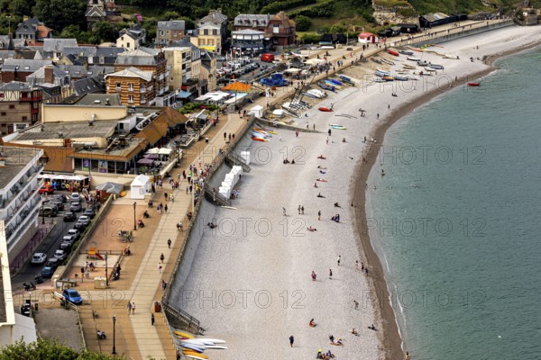 Beach scene with promenade and people, view of the sea and boats, Etretat in Normandy, France
