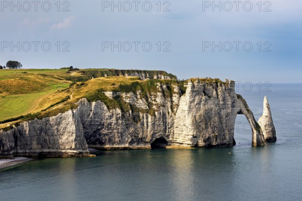 Dramatic cliffs with striking rock formations, surrounded by calm seas and cloudy skies, The cliffs and alabaster coast of Etretat in Normandy France