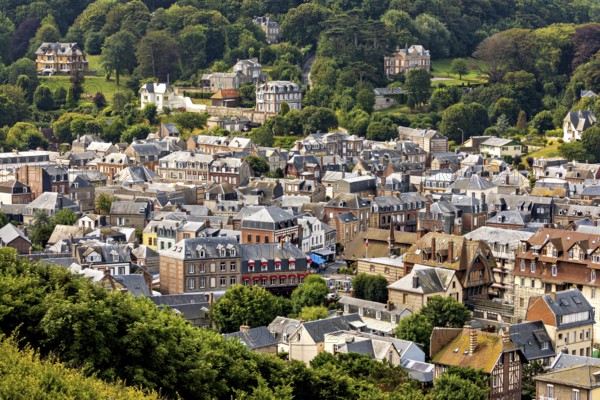 Expansive view of a town from a green hill with lots of nature, Etretat in Normandy, France