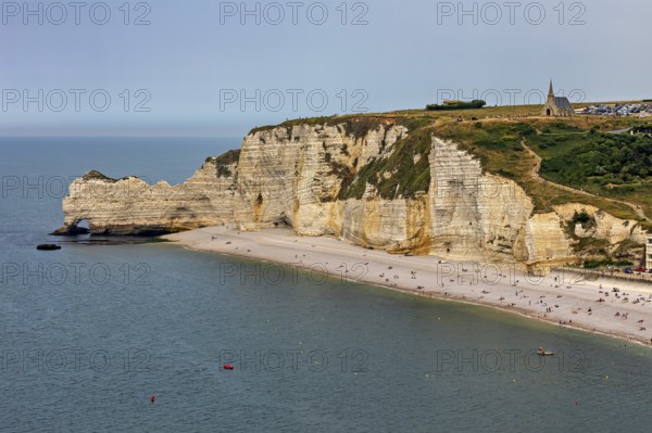 Imposing cliffs with a church at the top and a quiet beach by the sea, The cliffs and alabaster coast of Etretat in Normandy France
