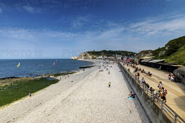 Wide beach with sea view and people walking under a blue sky, Etretat in Normandy, France