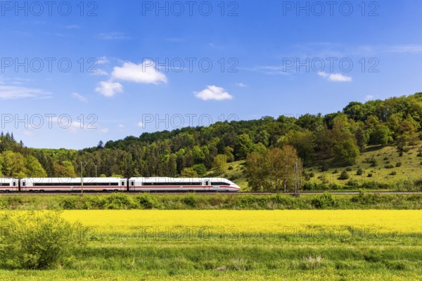InterCityExpress ICE en route on the Swabian Alb near Lonsee. Landscape on the railway's Filstalline line in spring with rape fields in bloom. Lonsee, Baden-Württemberg, Germany