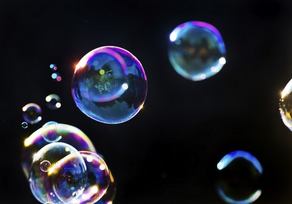 Iridescent soap bubbles in the colours of the rainbow against a black background, Recklinghausen, North Rhine-Westphalia, Germany