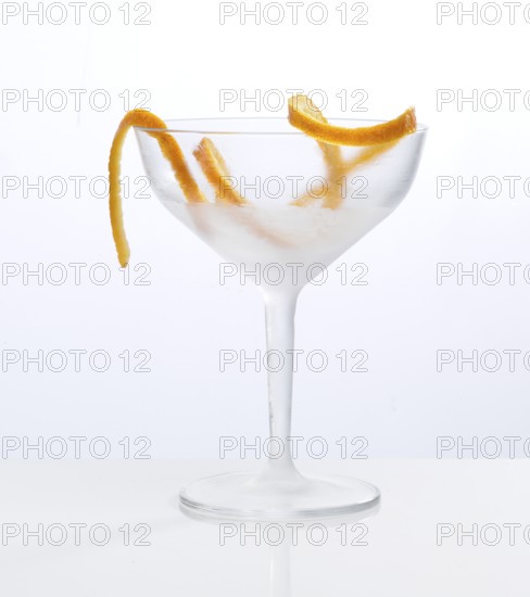 Frosted empty cocktail glass with orange zest as garnish against a white background, studio shot