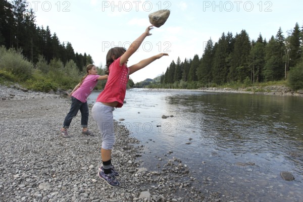Girls, children throwing stones into a river, activity with children in nature, Allgäu, Bavaria, Germany, Allgäu, Bavaria, Germany